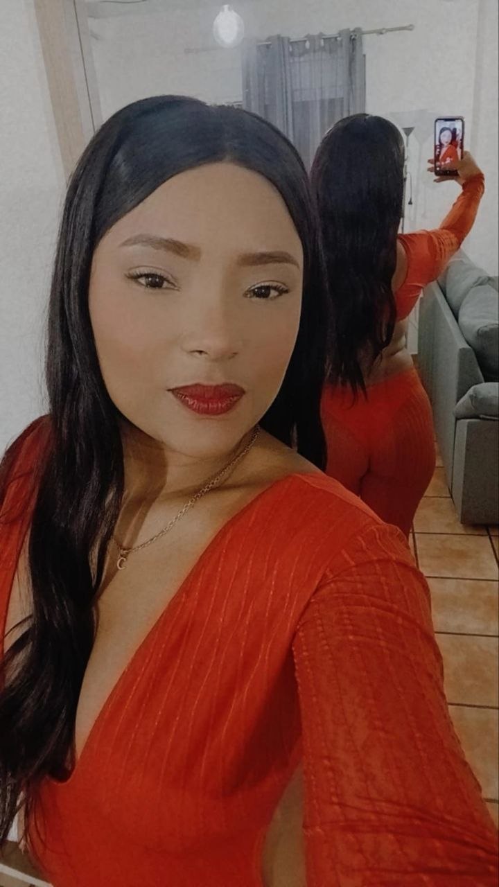 Camila, 26 years old escort takes a picture with a makeup that highlights her red lips and a fine golden necklace in Malaga.