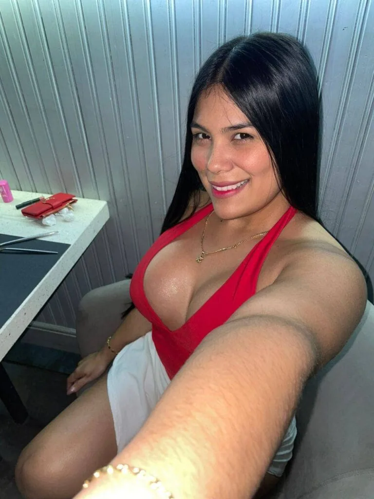 Dulce, escort di 24 anni, indossa un top rosso e una catena d'oro a Málaga.