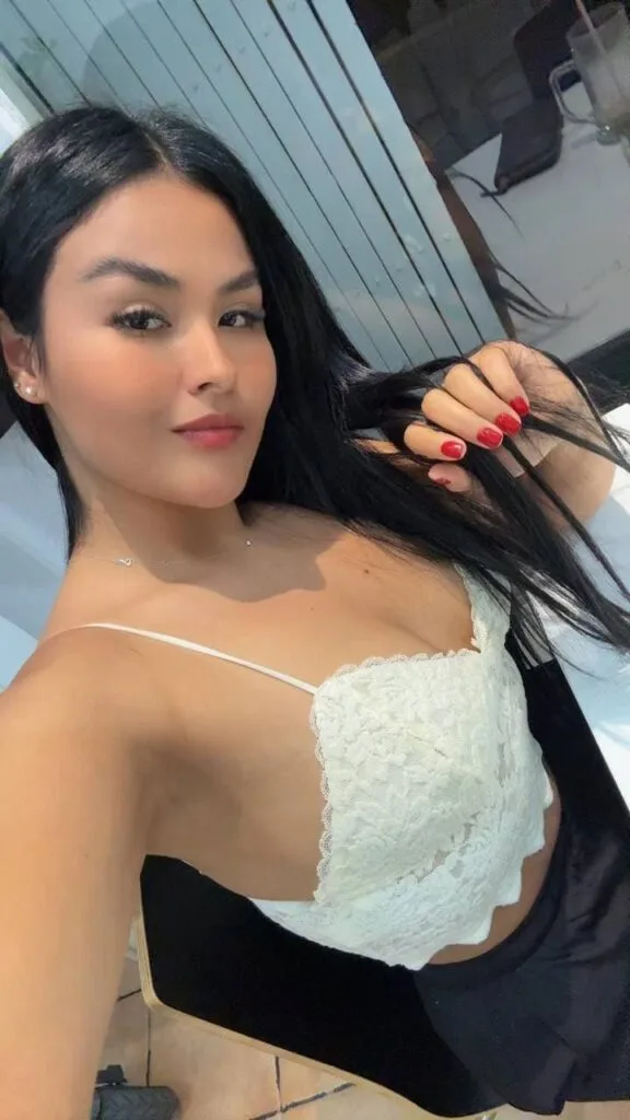 Juanita, i escortpige, bærer en hvid top, der fremhæver hendes lange, mørke hår i Malaga